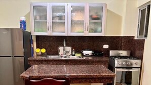 Una cocina compacta con encimeras de granito, estufa integrada y un refrigerador.