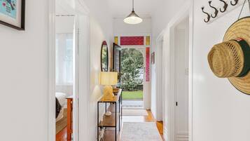 A hallway with a wooden floor, a hanging lamp, a bench, and a view of the outdoors.