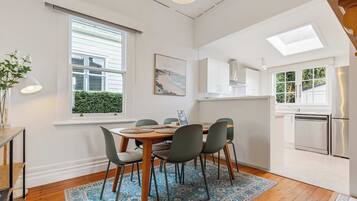 A dining area with a table set for four, surrounded by chairs, a patterned rug, and a window with blinds.