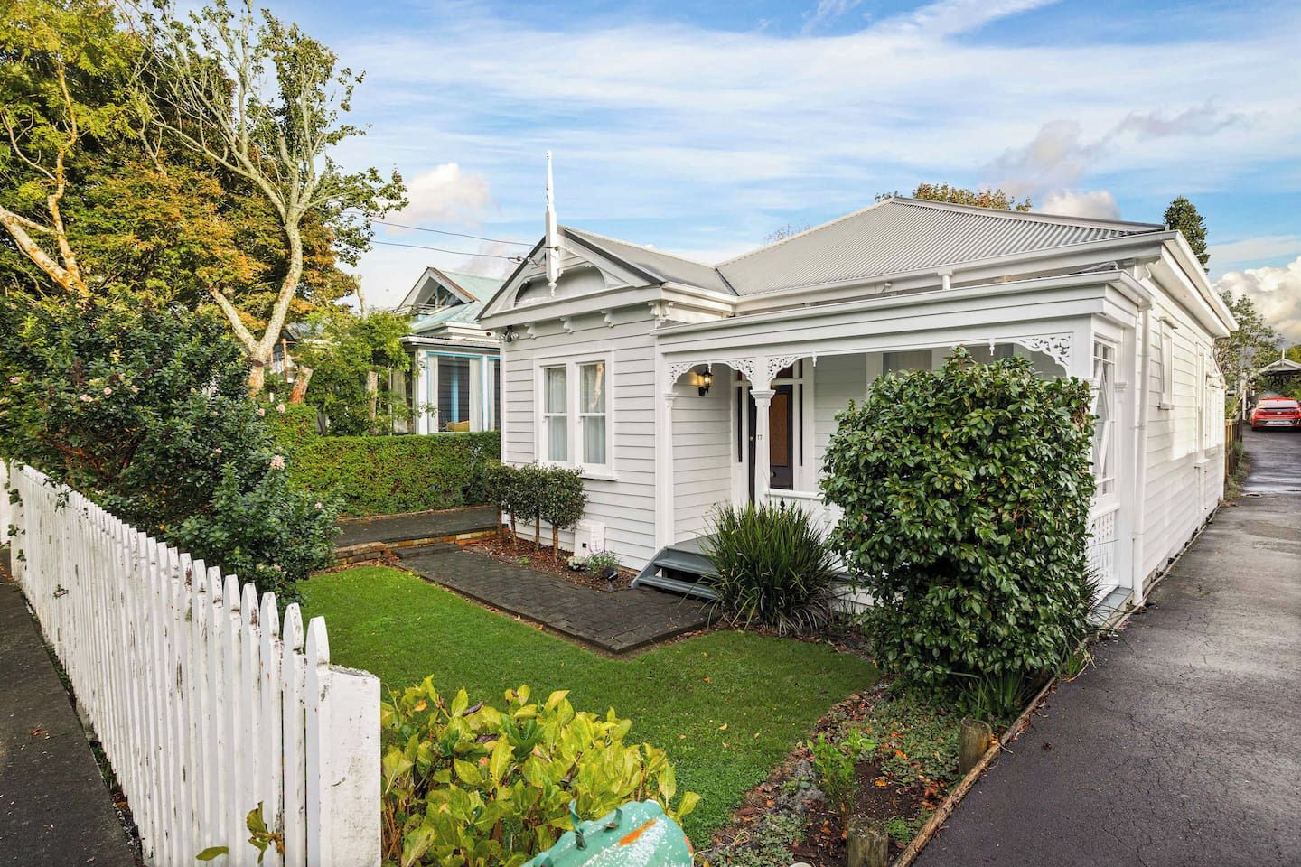A single-story house with a front porch, a small front yard, and a white picket fence.