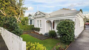 A single-story house with a front porch, a small front yard, and a white picket fence.