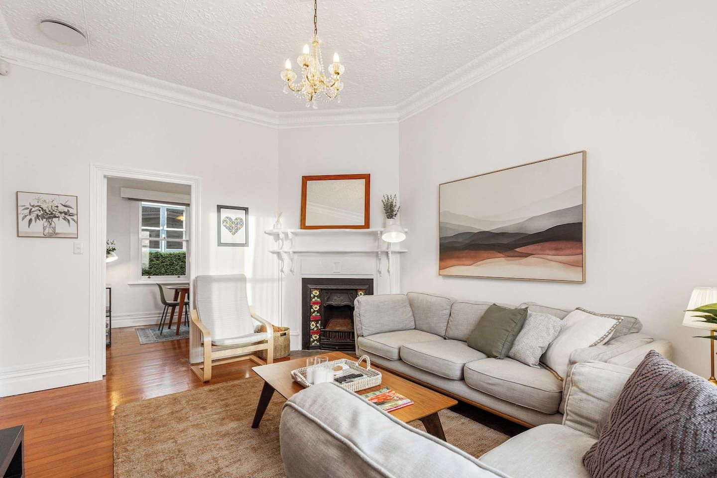 A living room with a fireplace, a sofa, a chair, and a large painting on the wall.