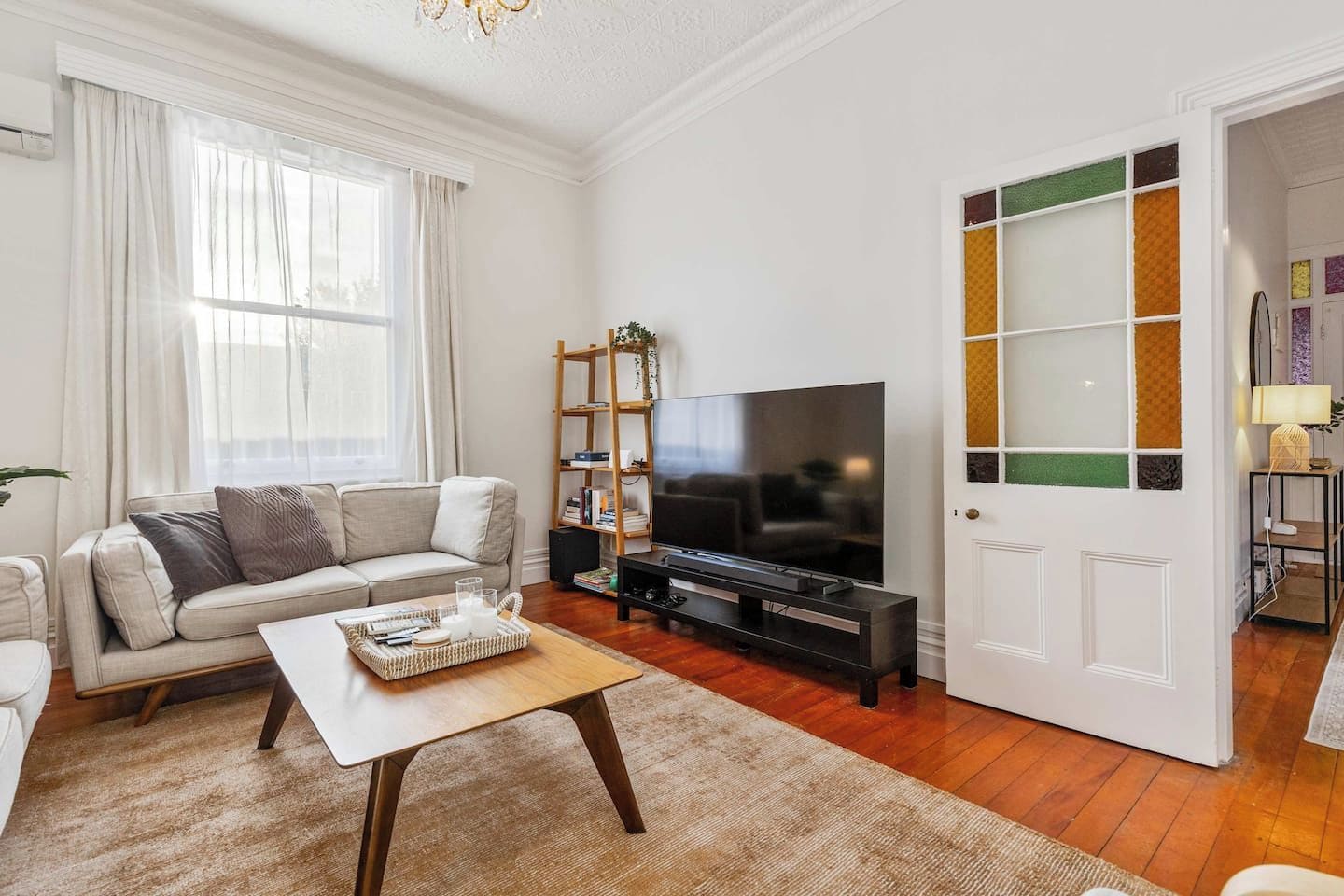 A living room with a sofa, a coffee table, a TV, and a bookshelf.