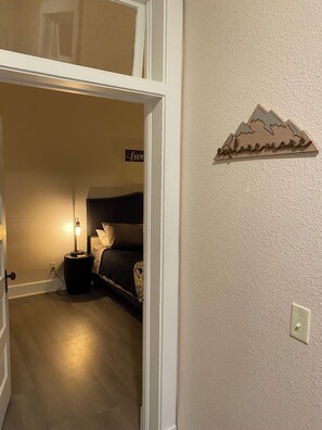 Ein Schlafzimmer mit einem Bett, einer Nachttischlampe und einem Wandschild.