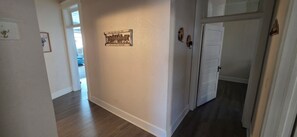A hallway with a wooden floor, white walls, and a door on the right.