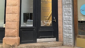 Una esquina de edificio con una puerta de marco negro, pilares de piedra y un letrero que dice 'South Dakota Rhodes Suites' con una lista de servicios.