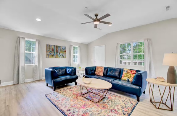 A spacious living room with a ceiling fan, two sofas, a coffee table, and a rug.