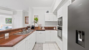Una cocina moderna con armarios blancos, encimera de granito, lavavajillas, horno y refrigerador.