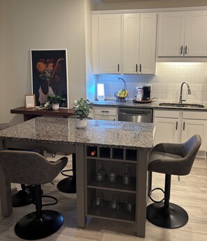 A modern kitchen with white cabinets, a granite countertop, and a built-in wine rack.