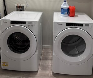 Two Whirlpool front-loading washing machines side by side with detergent bottles on top.