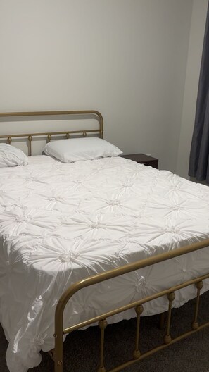 A single bed with a metal frame and white bedding.