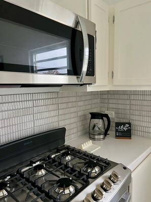 A kitchen with a gas stove, a microwave, and a coffee maker. - Cozy 1-bedroom apartment in lovely Osbourn with AC (Osbourn)