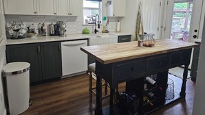 A kitchen with white cabinets, a wooden island, and a view of the outdoors.