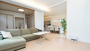 A modern living room with a sectional sofa, a small white table, and a kitchen in the background.