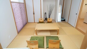 A traditional Japanese-style room with tatami flooring, a low table, and cushions.