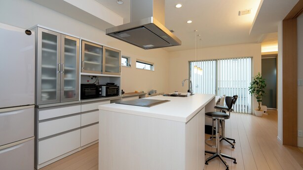 A modern kitchen with white cabinetry, a central island, and a dining area with bar stools.