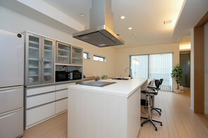 Een moderne keuken met witte kasten, een centraal eiland en een eethoek met barstoelen.
