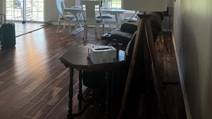 Une pièce spacieuse dotée d’un ventilateur de plafond, d’un coin repas avec des chaises blanches, une table et une fenêtre avec des rideaux.