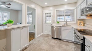 Une cuisine moderne avec des meubles blancs, un lave-vaisselle et une cuisinière.
