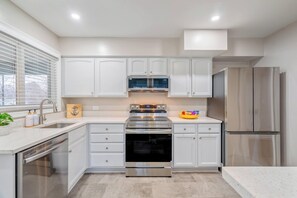 A modern kitchen with white cabinets, stainless steel appliances, a built-in oven, and a microwave. - 8 Bells Bungalow - Cozy, Stylish, Prime Location (Annapolis)