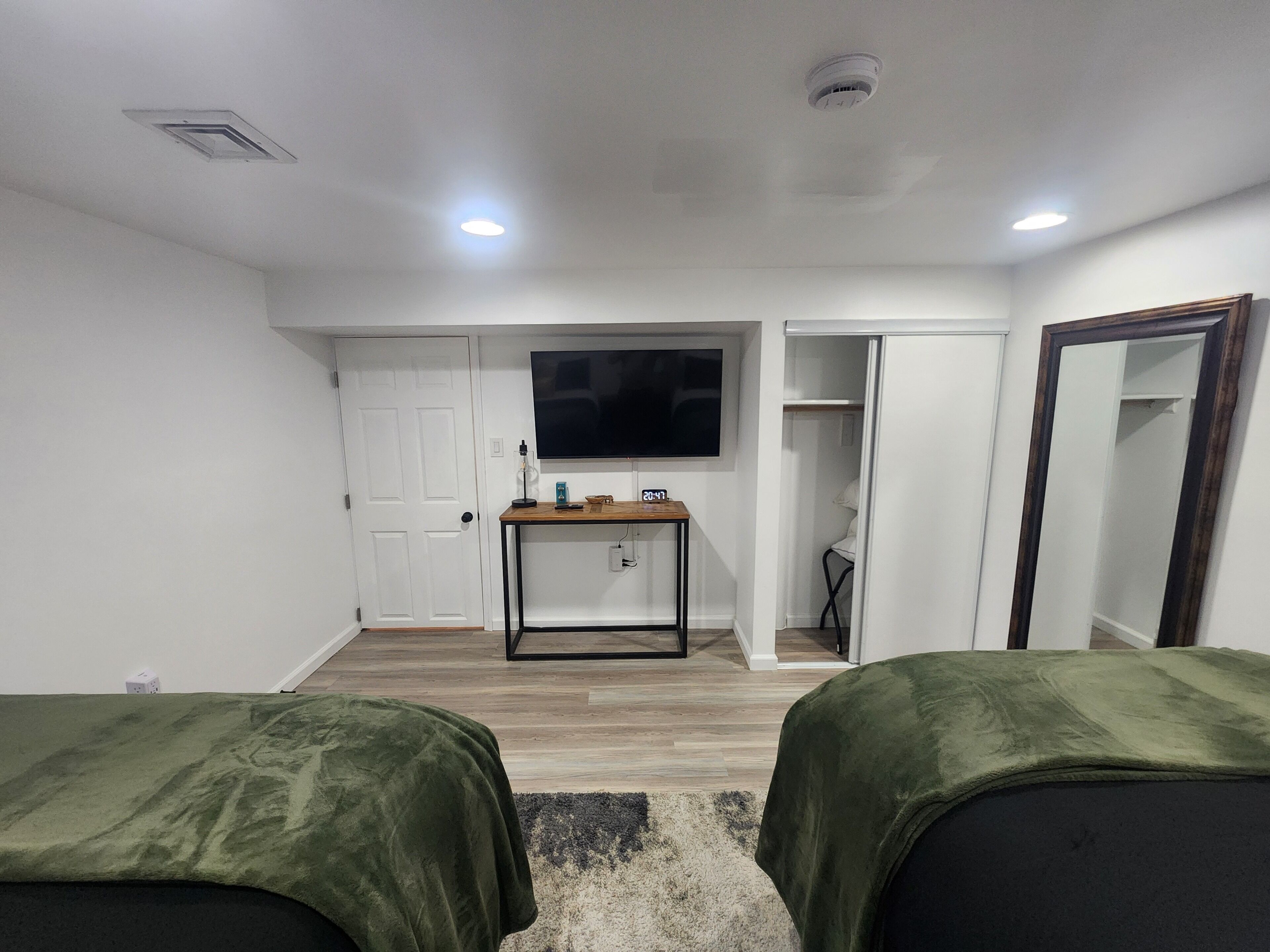 A room with two beds, a TV, a desk, and a closet.