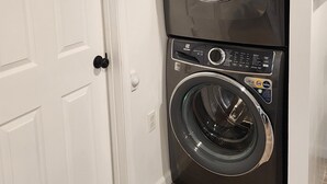 Un lavadero pequeño y compacto, de dos puertas, con diseño moderno e incluye lavadora y secadora apiladas.