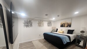 Un dormitorio moderno con cama, mesitas de noche, televisor de pantalla plana y arte abstracto en la pared.