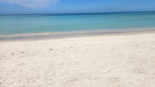 A beach with clear turquoise water and a sandy shore. - Luxe Coastal Retreat • 12 Min to Beach • Private Yard w/Games (Clearwater)