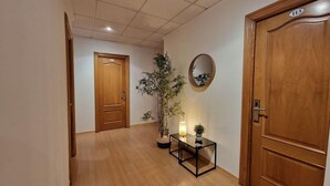 Un pasillo con puertas de madera, una planta en maceta, una mesita con lámpara y un espejo en la pared.