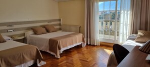 Une chambre d’hôtel avec deux lits, un radiateur, une fenêtre avec des rideaux et une vue sur l’extérieur.