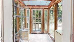 A narrow corridor with a wooden door, metal shelving, and large windows. - Panoramic ocean view 4-bedroom house in charming Gualala perfect for relaxing . (Gualala)