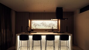 A modern kitchen with a marble countertop, a window with a grid pattern, and three black bar stools.