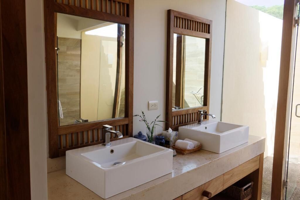 A bathroom with two sinks, wooden-framed mirrors, and a beige countertop.