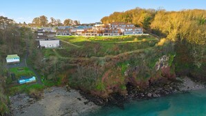 A coastal residential area with modern multi-story houses, a beach, and a rocky shoreline. - Avocet 2 is a stylish coastal apartment offering uninterrupted sea views (Brixham)