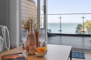 Ein Tisch mit einer Flasche Roséwein, zwei Gläsern, einer Schale mit Snacks und einem Buch mit dem Titel 'English Riviera'.