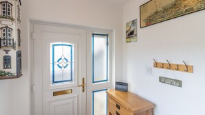 Ein Zimmer mit weißer Tür, einem Holzschrank, einem Kleiderhaken und einem an der Wand befestigten Schild.