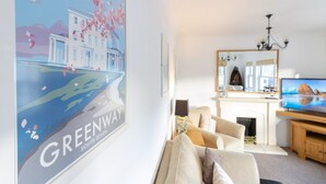 Ein Wohnzimmer mit einer Couch, einem Fernseher, einem Kamin und einem Bild von einem Gebäude.