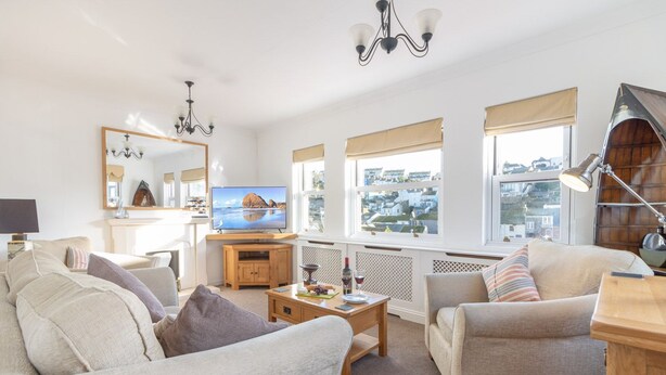 Ein Wohnzimmer mit Fernseher, Sofa und Blick auf die Stadt.