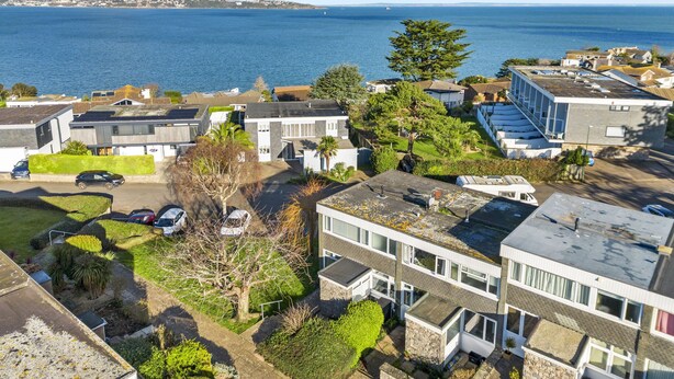 Zona residencial costeira com casas modernas, um porto de iates e vista clara para o mar.