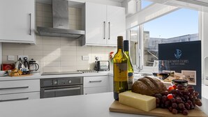 Cozinha moderna com armários brancos, exaustor de aço inoxidável e uma janela ampla.