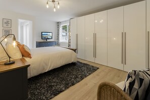 Ein Schlafzimmer mit einem Bett, einem Schreibtisch mit Lampe, einem Fernseher und einem Kleiderschrank.