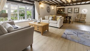 Un salon comprenant un canapé, une table basse en bois, un tapis à motifs et un coin repas avec une table et des chaises.