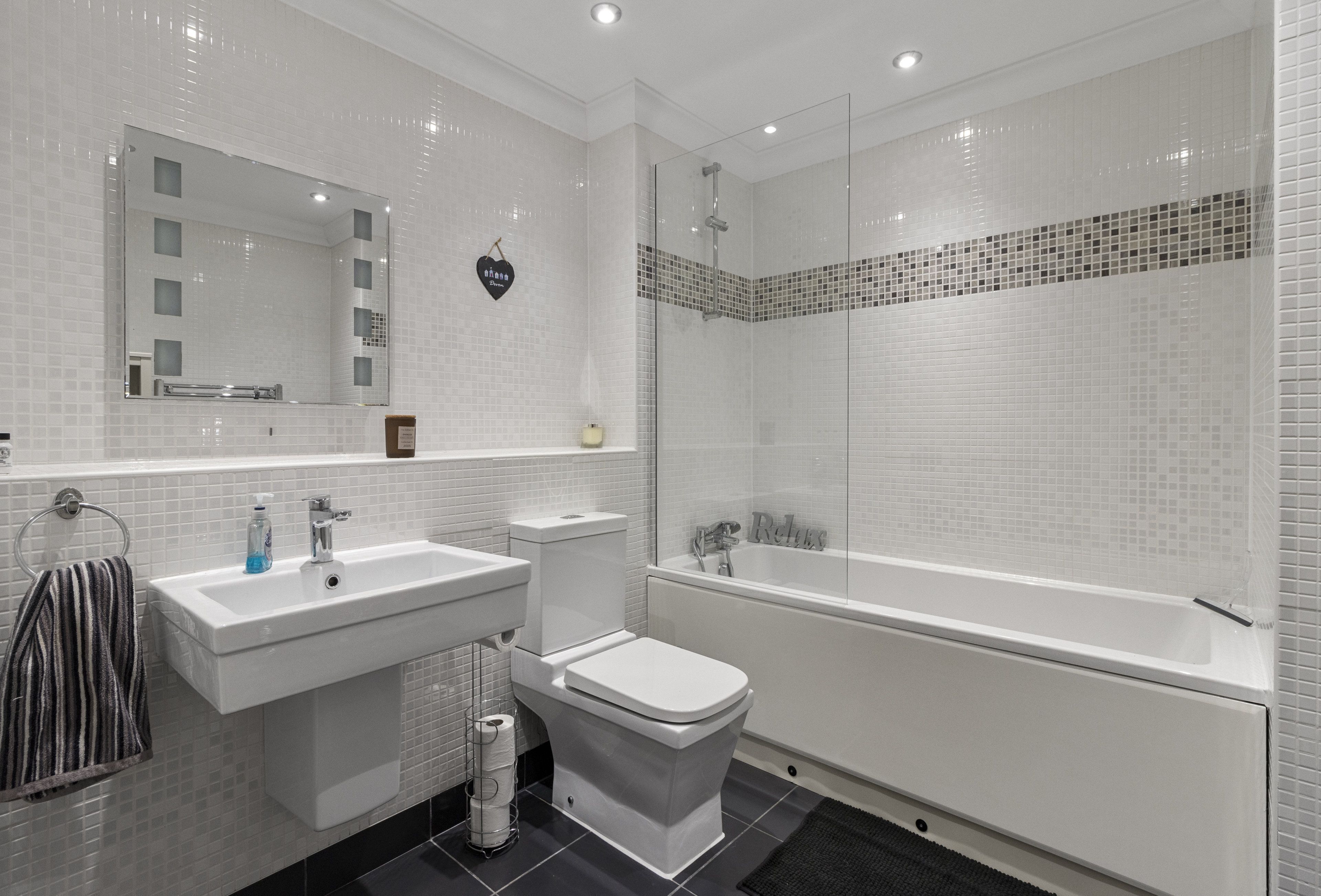 Ein modernes Badezimmer mit Waschbecken, Toilette und Badewanne in Weiß.