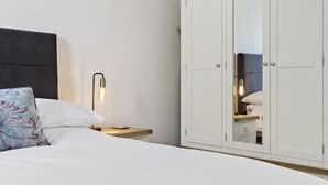 Una camera da letto con un letto, comodino, lampada, armadio e specchio.