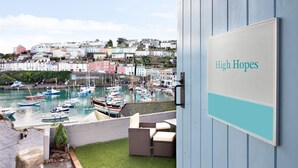 A view of a marina with boats, a sign reading "High Hopes", and a building with a blue exterior. - High Hopes, a stunning Grade II listed Brixham holiday cottage (Brixham)