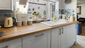 A kitchen with a wooden countertop, a sink, and a window with a view of the outside. - Hope Cottage, a charming 1850s fisherman's cottage in Brixham (Brixham)