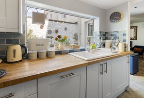 A kitchen with a wooden countertop, a sink, and a window with a view of the outside. - Hope Cottage, a charming 1850s fisherman's cottage in Brixham (Brixham)