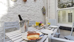 A table set with plates of food, a bottle of champagne, and a vase with flowers. - Hope Cottage, a charming 1850s fisherman's cottage in Brixham (Brixham)