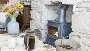 A cozy room with a stone fireplace, a kettle, and a vase of flowers. - Hope Cottage, a charming 1850s fisherman's cottage in Brixham (Brixham)