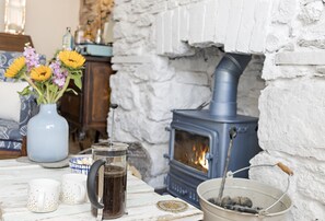 A cozy room with a stone fireplace, a kettle, and a vase of flowers. - Hope Cottage, a charming 1850s fisherman's cottage in Brixham (Brixham)